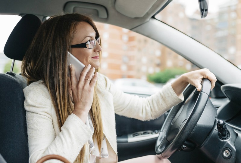 Eine Frau sitzt am Steuer des Autos ihres Mannes
