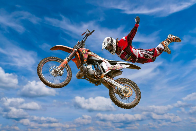 Zu sehen ist ein Motorradfahrer, der einen eindrucksvollen Stunt in der Luft ausführt.