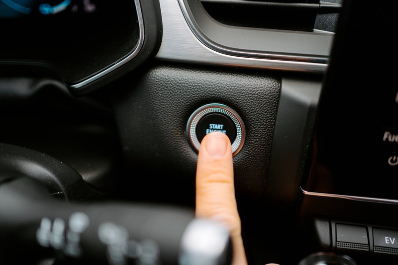 Zu sehen ist eine Hand, die den Power-Knopf in einem Auto betätigt.