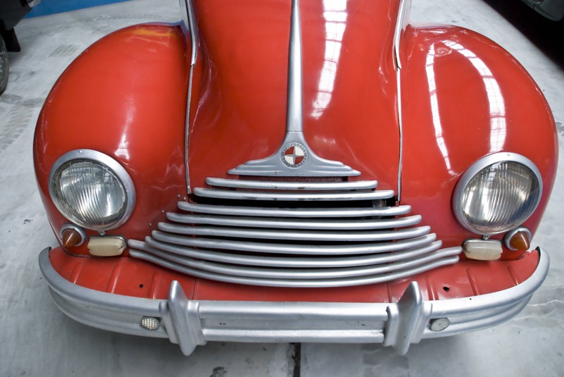 Zu sehen ist die Front eines roten Oldtimer-Wagens.