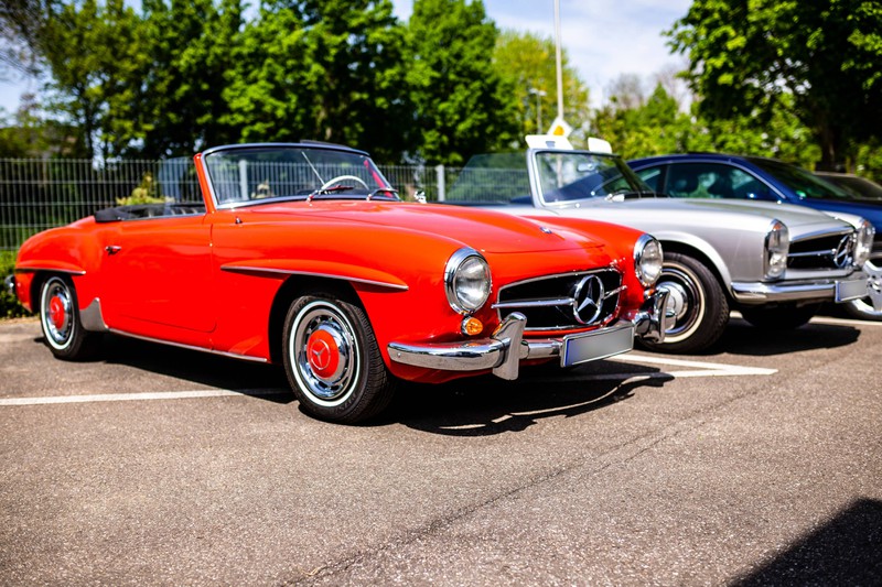 Ein roter Mercedes Oldtimer steht auf einem Parkplatz.