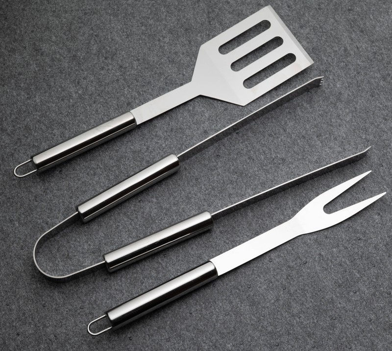 Edelstahl Grillbesteck auf grauem Hintergrund.
