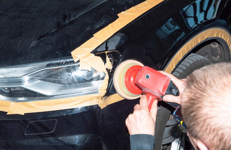Ein Foto von einem Mann, der den Lack des Autos poliert, was bei Hitze schädlich sein kann